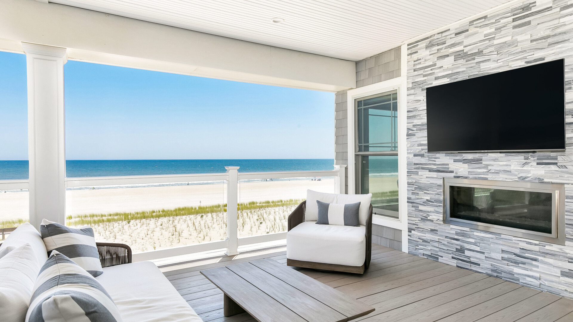 Modern beach home boasting a large outdoor living space with custom stone wall and fireplace, Long Beach Island NJ